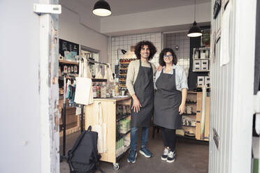 Full length of smiling male and female entrepreneurs standing in organic store - MASF24501