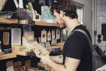 Männlicher Kunde beim Lesen der Verpackung im Bioladen - MASF24511