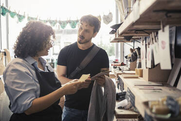 Male customer discussing with saleswoman at organic shop - MASF24521