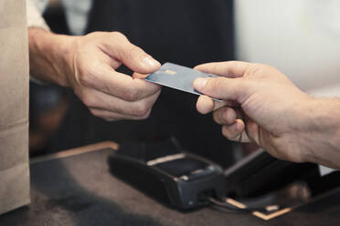 Male customer making payment through credit card at organic shop - MASF24533