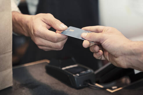 Männlicher Kunde beim Bezahlen mit Kreditkarte im Bioladen - MASF24533