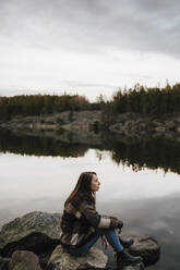 Female hiker contemplating while exploring in forest by lake during vacation - MASF24540