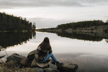 Rear view of young female hiker admiring lake during vacation - MASF24545