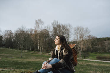 Young woman with eyes closed sitting in forest - MASF24585