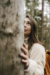 Junge Frau betrachtet einen Baum im Wald - MASF24609