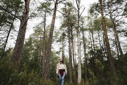 Junge Forscherin beim Wandern inmitten von Bäumen im Wald - MASF24611