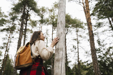 Female hiker standing by tree in forest - MASF24612