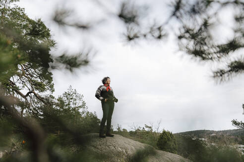 Weibliche Forscherin steht auf einem Felsen im Wald - MASF24620