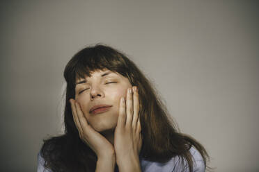 Young woman with eyes closed against white background - MASF24695