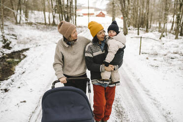 Reife Frau trägt Tochter beim Spaziergang mit Freundin im Schnee - MASF24720