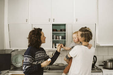 Lesbian mothers with daughter in kitchen at home - MASF24735
