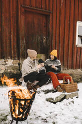 Gay couple with daughter against cottage during winter - MASF24742