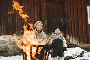 Mutter mit Tochter in der Nähe einer brennenden Feuerstelle, die wegschaut - MASF24746