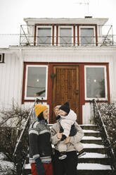 Lesbisches Paar mit Tochter steht im Winter vor dem Haus - MASF24781