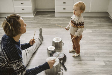 Mutter und Tochter spielen mit Stäbchen und Besteck in der Küche - MASF24792