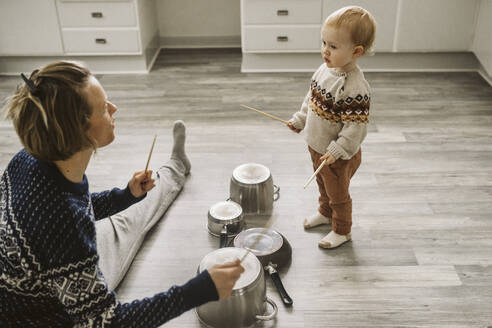 Mother and daughter playing with chopsticks and utensils in kitchen - MASF24792