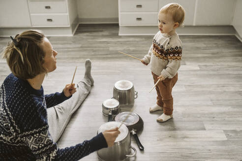 Mutter und Tochter spielen mit Stäbchen und Besteck in der Küche - MASF24792