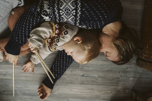 Müde Mutter und Tochter mit Stäbchen schlafen zusammen auf dem Boden zu Hause - MASF24797