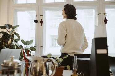 Male entrepreneur standing by window in home office - MASF24889