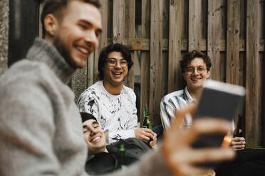 Lächelnde männliche Freunde nehmen Selfie durch Smartphone in Balkon - MASF24911