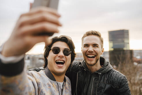 Fröhliche männliche Freunde machen ein Selfie mit ihrem Smartphone - MASF24937