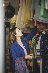 Female owner arranging clothes in rack at boutique - MASF25011