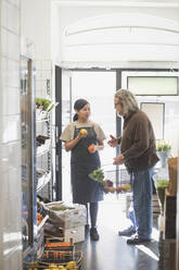 Senior male customer talking with female owner while buying food in store - MASF25045