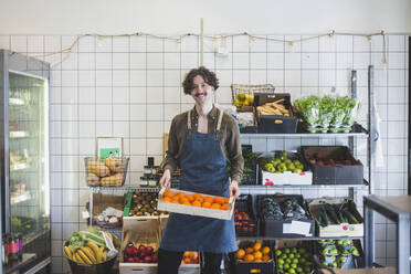 Portrait of smiling male owner with fruit box in store - MASF25084