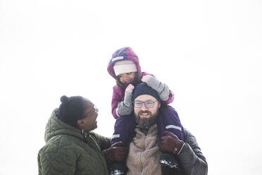 Glückliche Frau sieht ihre Tochter an, die im Winter auf der Schulter eines Mannes sitzt - MASF25100