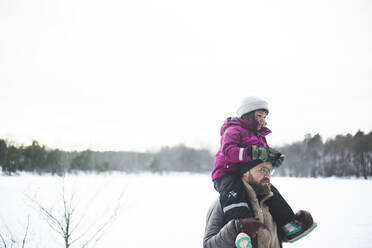 Mature man carrying daughter on shoulders during winter - MASF25104