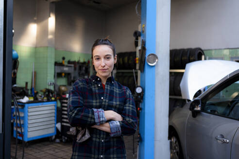 Mechanikerin mit verschränkten Armen in der Werkstatt stehend - KNSF08853