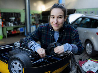 Mechanikerin arbeitet in der Werkstatt an einem Spielzeugauto - KNSF08868