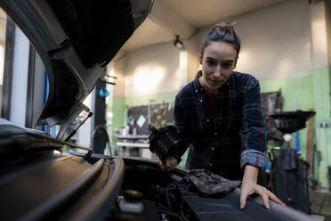 Mechanikerin repariert Auto in der Werkstatt - KNSF08880