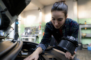 Ein weiblicher Mechaniker untersucht einen Automotor in einer Reparaturwerkstatt - KNSF08881