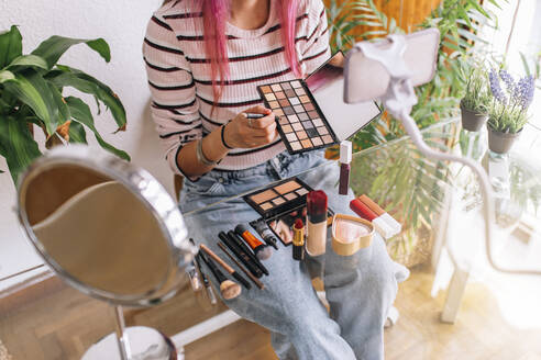 Female vlogger making make-up tutorial through mobile phone at home - EGHF00070