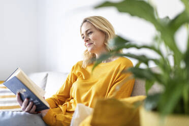 Blond woman reading book at home - WPEF04980