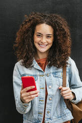 Beautiful young woman holding mobile phone - JCMF02025