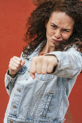 Young woman punching with fist while making face - JCMF02079