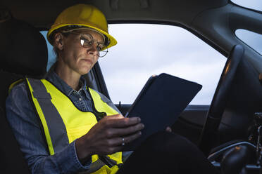 Mature female professional using digital tablet while sitting in car - UUF23782