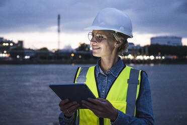 Smiling female professional looking away while holding digital tablet - UUF23789