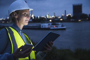 Contemplating female professional holding smart phone and digital tablet - UUF23793