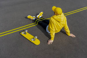 Gelbe Klebebänder über den Beinen eines Jungen mit einem Skateboard auf der Straße - VPIF04236