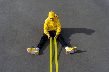 Junge hält gelbe Klebebänder, während er auf der Straße sitzt - VPIF04240