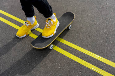 Yellow adhesive tape on boy's shoe while skateboarding on road - VPIF04242