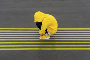 Deprimierter Junge kauert auf gestreiften gelben Straßenmarkierungen - VPIF04255