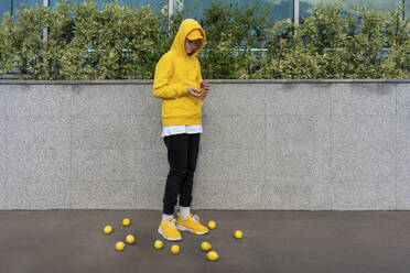 Junge steht inmitten von Zitronen an einer Stützmauer - VPIF04260