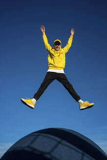 Boy with arms raised jumping at skateboard park - VPIF04280