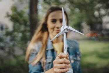 Junge Frau hält Modell einer Windkraftanlage - MFF08223