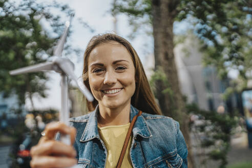 Lächelnde junge Frau hält ein Windradmodell - MFF08225