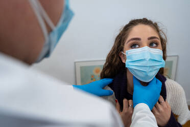 Unrecognizable medic in gloves examining lymph nodes of female patient during appointment in modern hospital - ADSF25279